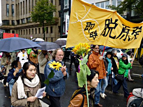 Demonstration mit Sonnenblumen und Japanisch-Plakat.