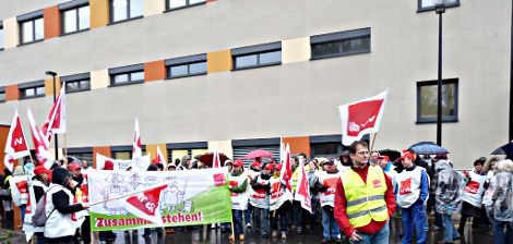 Sana-Beschäftigte mit Gewerkschaftsfahnen und Transparent: »Zusammen stehen!«.