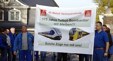 Bombardier-Kollegen mit IG-Metall-Transparent: »IG Metall Verrauensleute. 175 Jahre Talbot-Bombardier – wir bleiben!«, darunter abgebildet zwei Züge, Unterschrift: »Solche Züge nur mit uns!«.