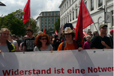 Demonstranten mit roten Fahnen und Transparent: »Widerstand ist eine Notwendigkeit«.