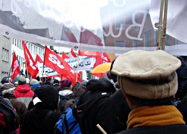 Demonstranten mit roten Fahnen und Transparenten.