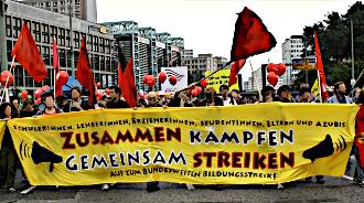 Demonstranten mit roten Fahnen und Transparent: »Zusammen kämpfen gemeinsam streiken«.