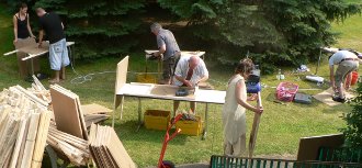 Sechs Menschen in einem Garten bauen Stelltafeln.