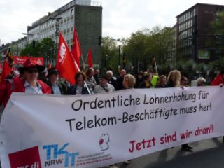 Mai-Demonstranten mit roten Fahnen und Transparent: »Ordentliche Lohnerhöhung für Telekom-Beschäftigte muss her! Jetzt sind wir dran!«.