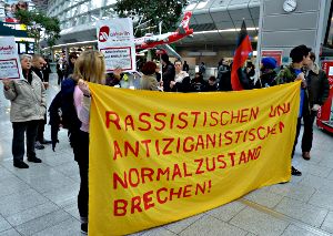 Demonstranten in der Flughafenhalle mit Transparent: »Rassistischen und antiziganistischen Normalzustand brechen!«.