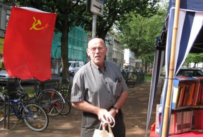 Horst Wilhelms am Bücherstand, im Hintergrund rote Fahne.