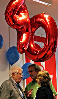 Hein Kolberg mit Gratulanten. Darüber Luftballons: »90«.